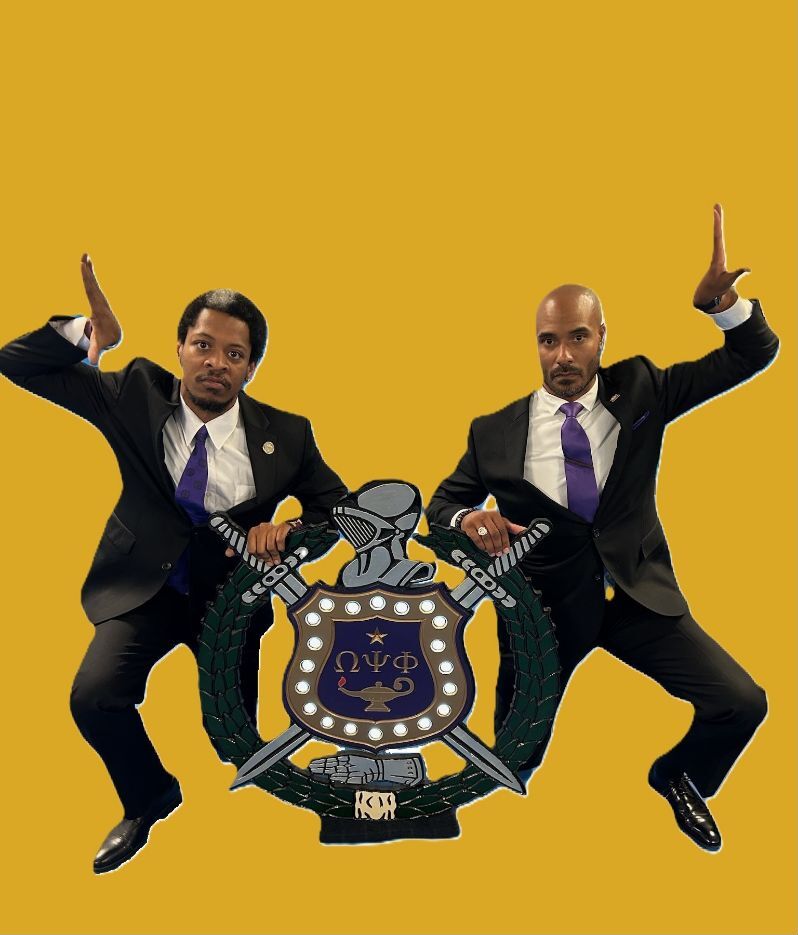 Spring 2023 line members posed beside the Omega Psi Phi shield on an old-gold background
